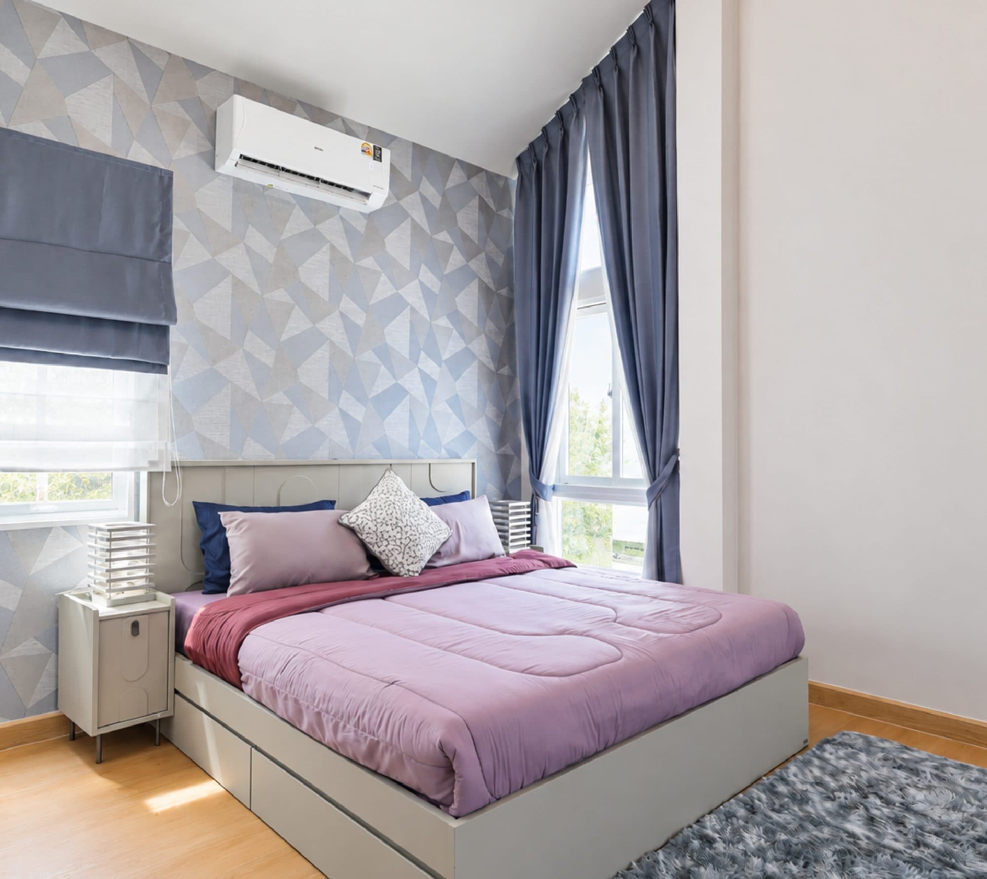 Bedroom with geometric wallpaper and lilac bedding.