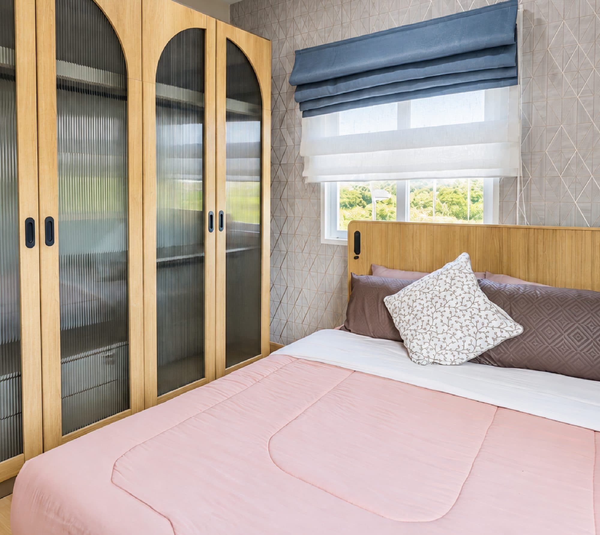 Bedroom with a timber headboard and arched fluted-glass wardrobes.