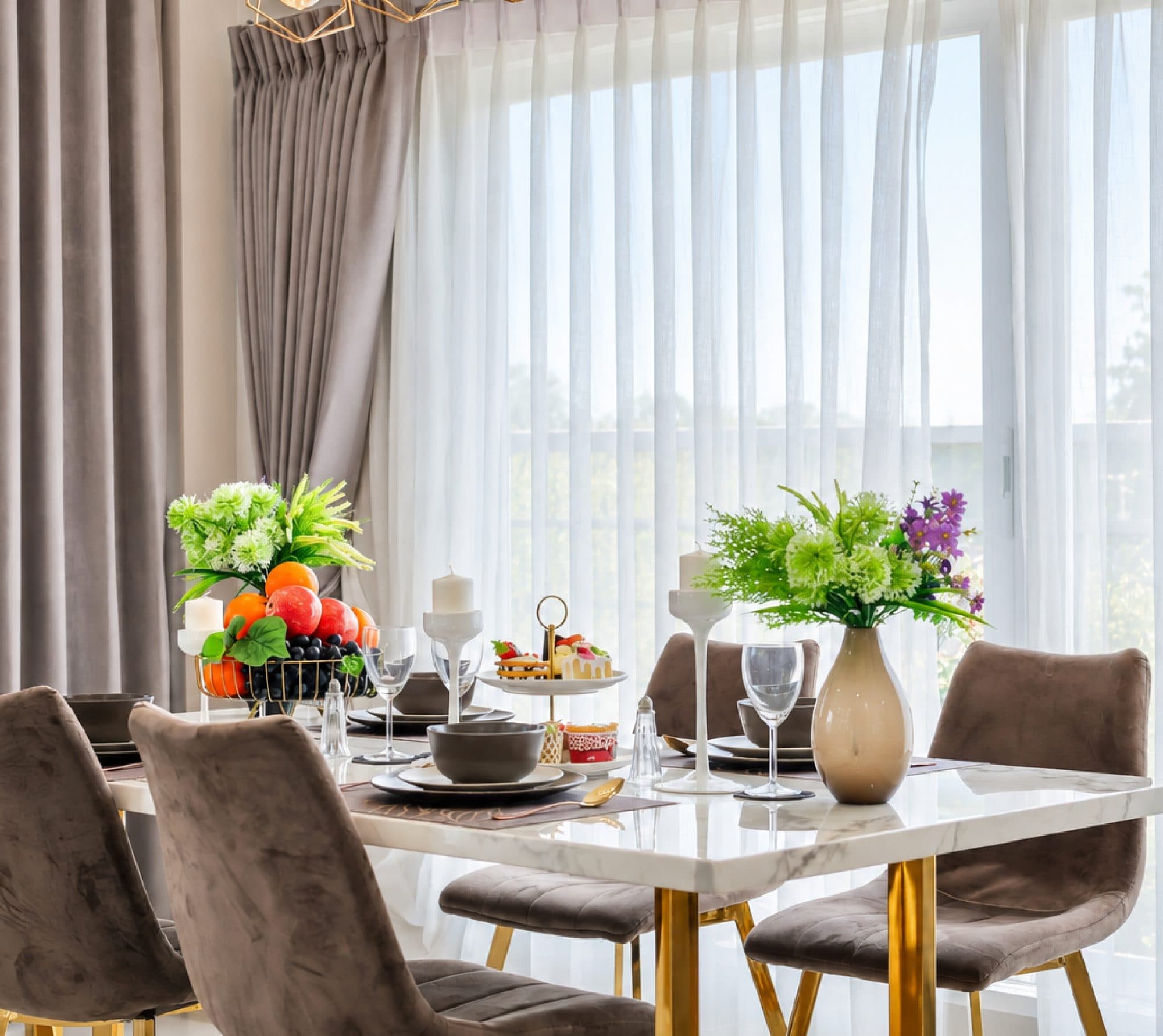 Marble-top dining table beside tall sheer-curtained windows.