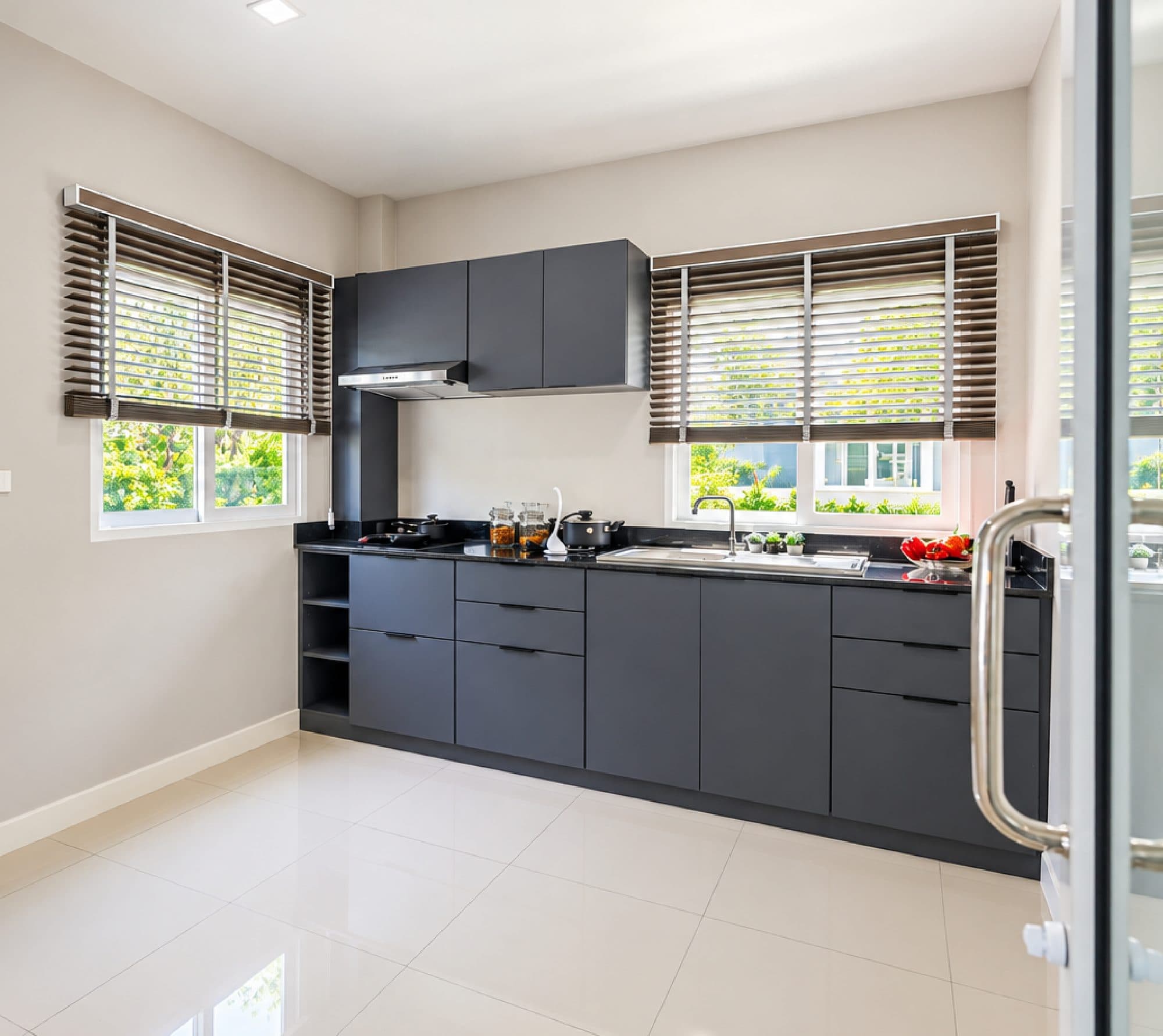 Kitchen with charcoal cabinets and windows on two sides.