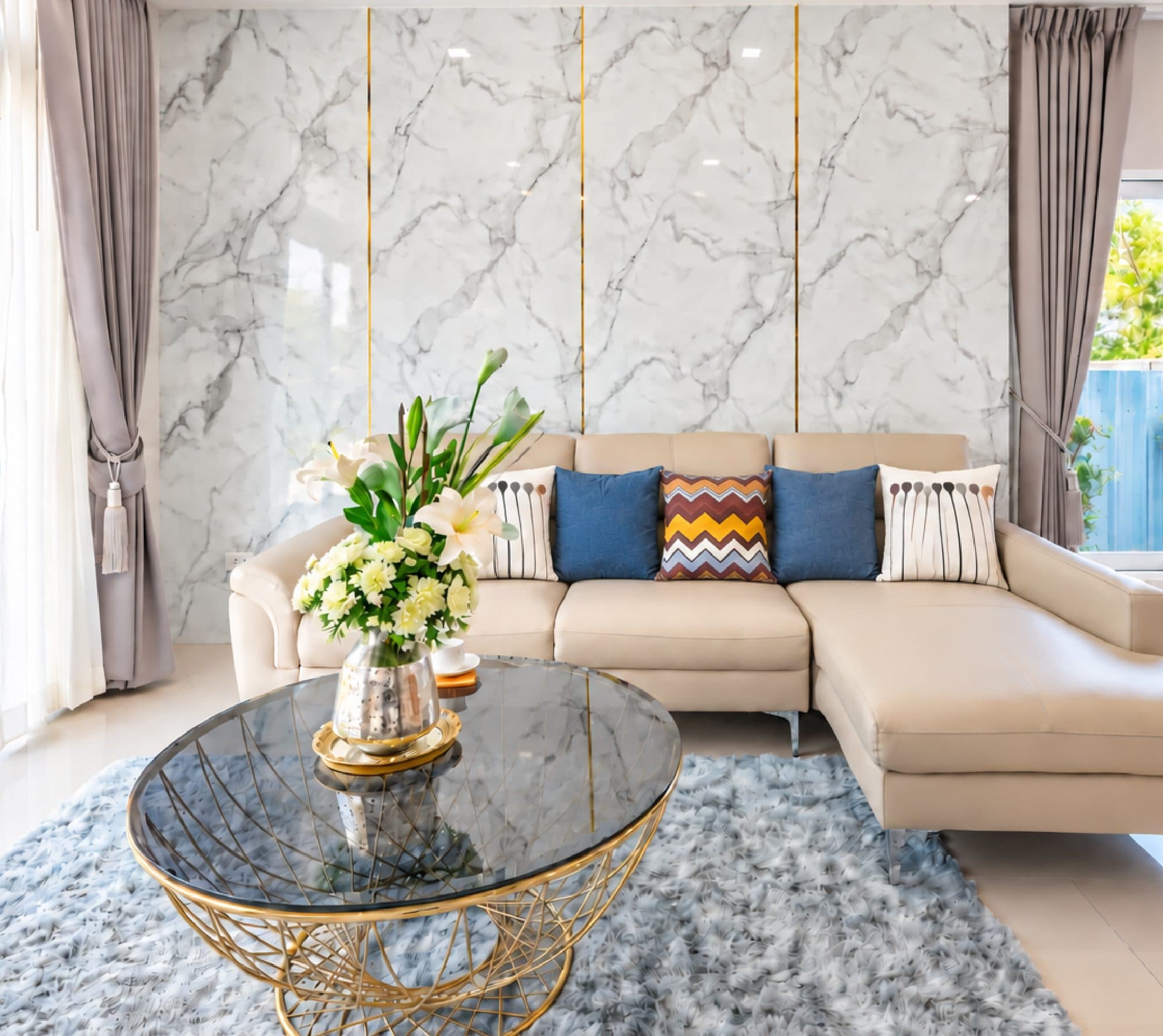 Living room with a cream sofa against a marble wall with gold inlay.
