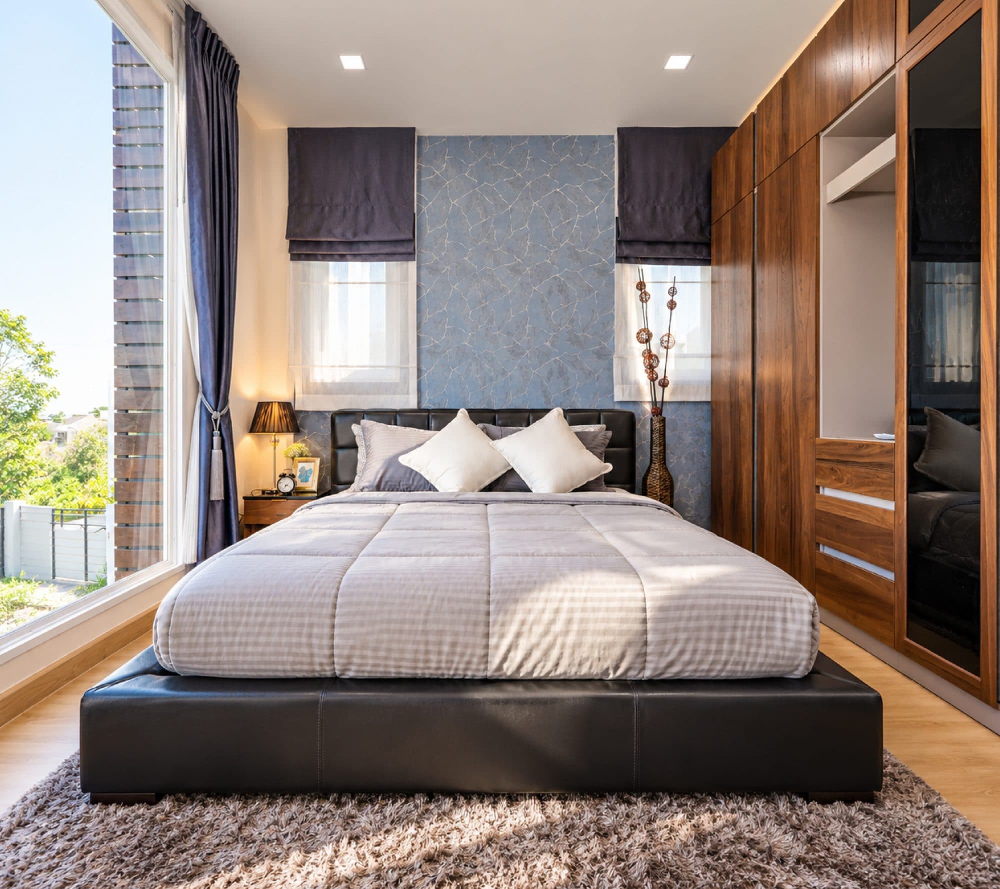 Main bedroom with a full wall of timber wardrobes and two windows.