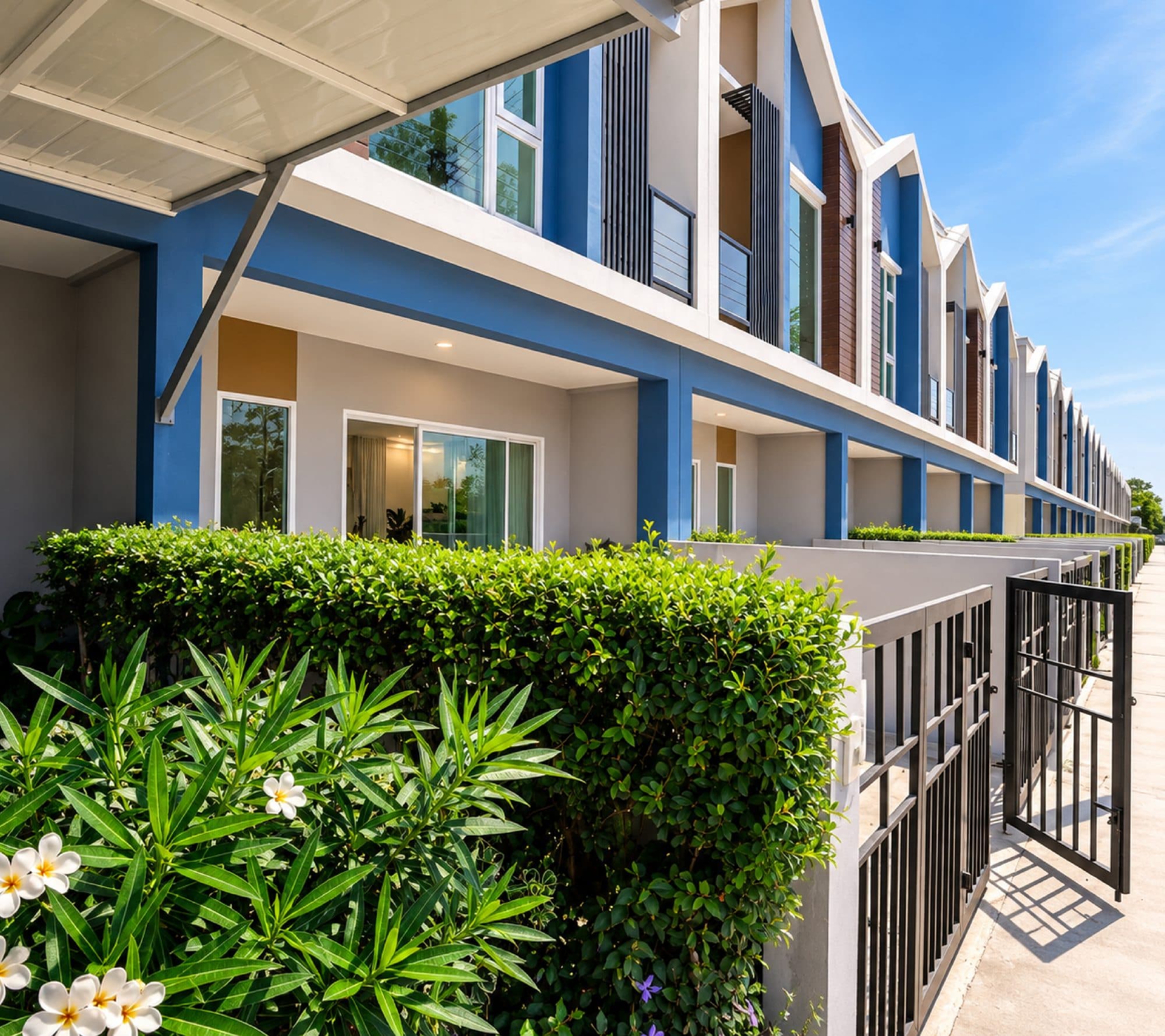 Townhome frontages behind clipped hedges, under the entrance canopy.