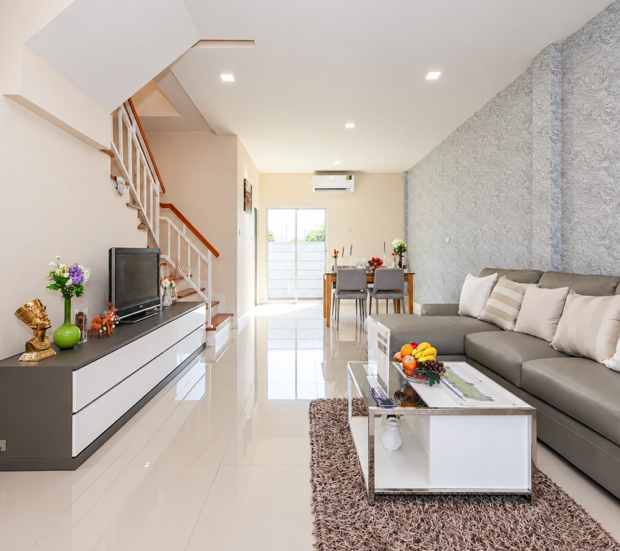 Living room with a grey sofa, looking through to the dining table and the rear door.